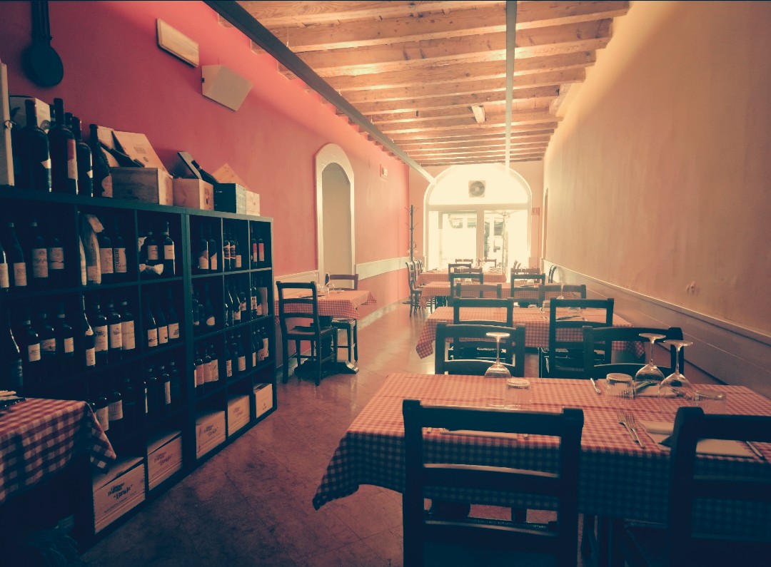 La sala lunga con tavoli a quadri e scaffali di vino